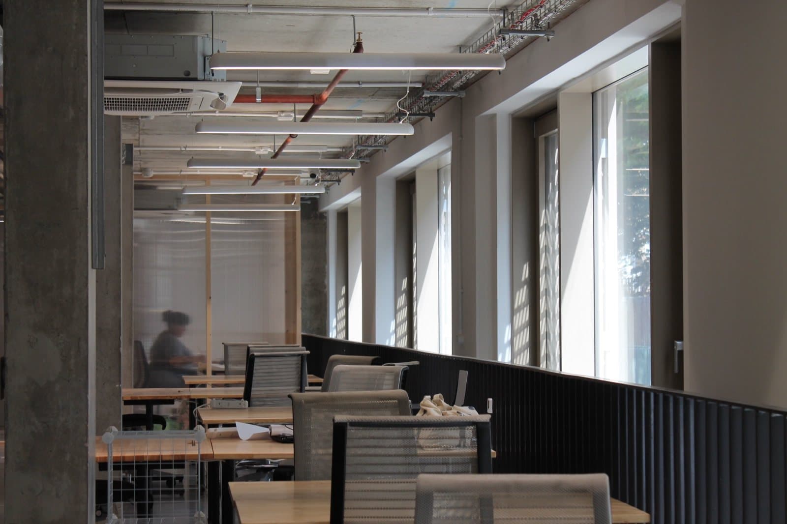 Desks and reclaimed office chairs under the exposed services at Lisson Arches