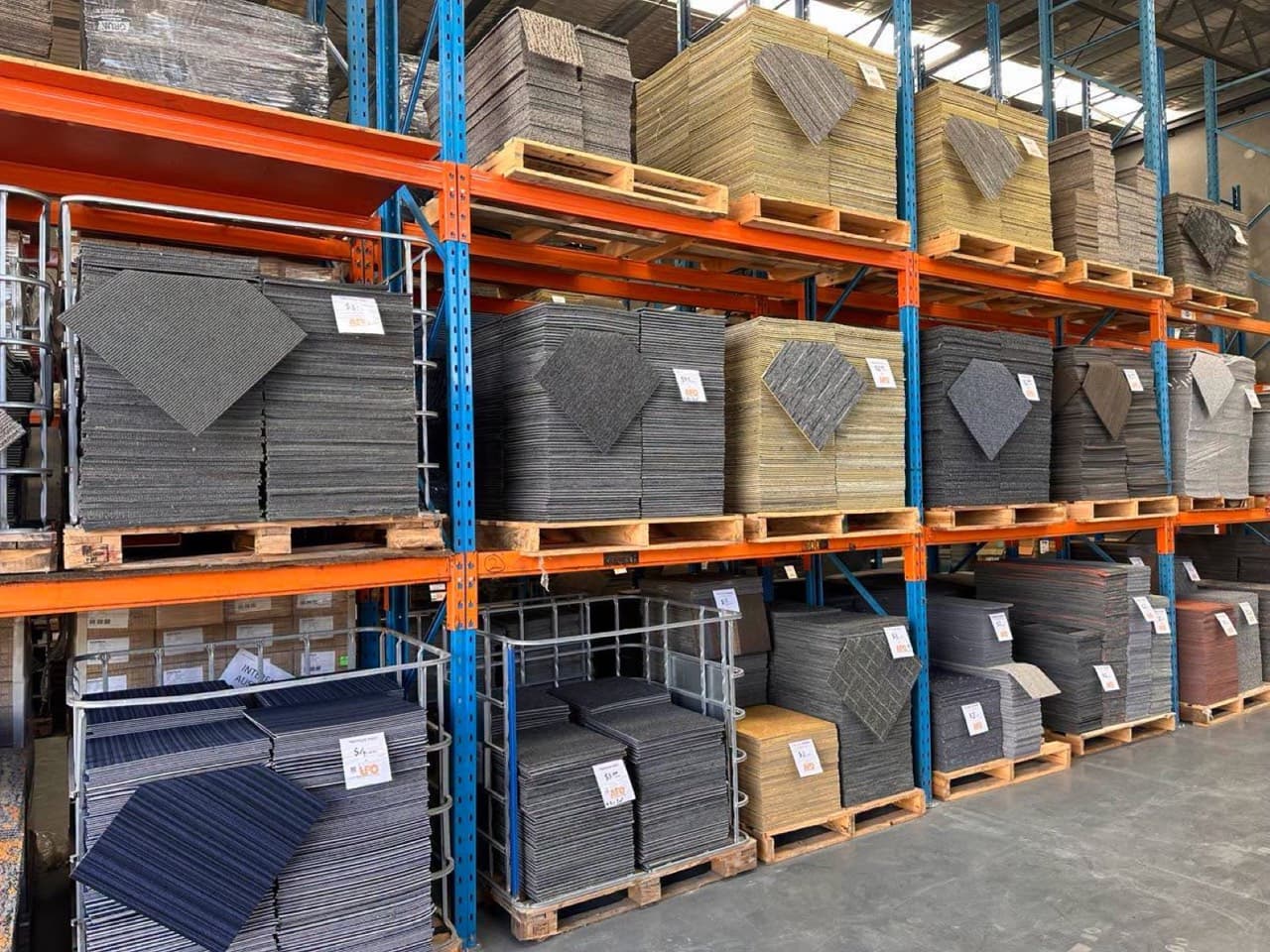 Pallets of reclaimed carpet tiles racked in a reseller warehouse